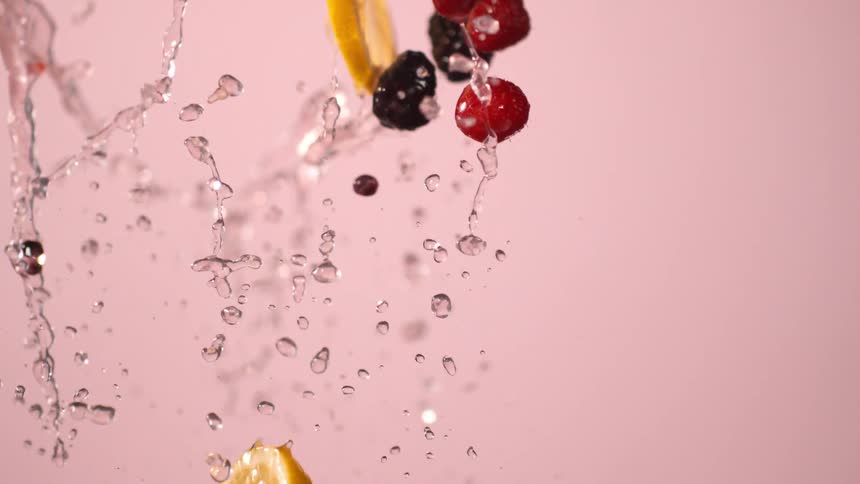 Water splashes several raspberries blackberries and lemon slices upwards