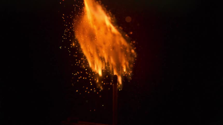 A wooden match explodes in flame then dies out with embers against black