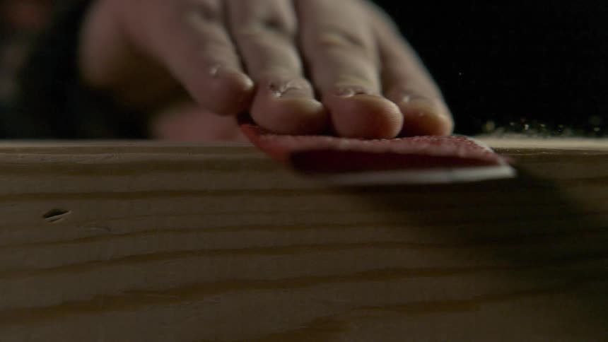 Hand sanding wood with sand paper in slow motion