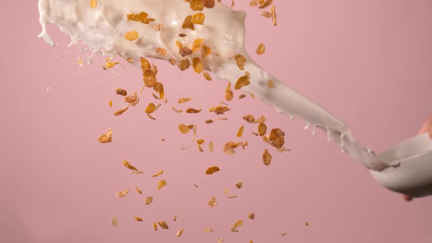 A white person tosses a bowl of milk at falling pieces of cereal
