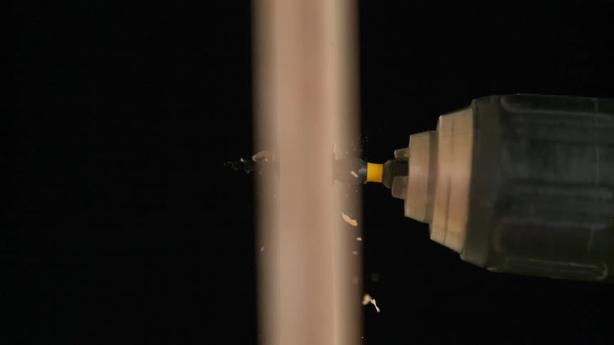 A drill is breaking through the wooden board