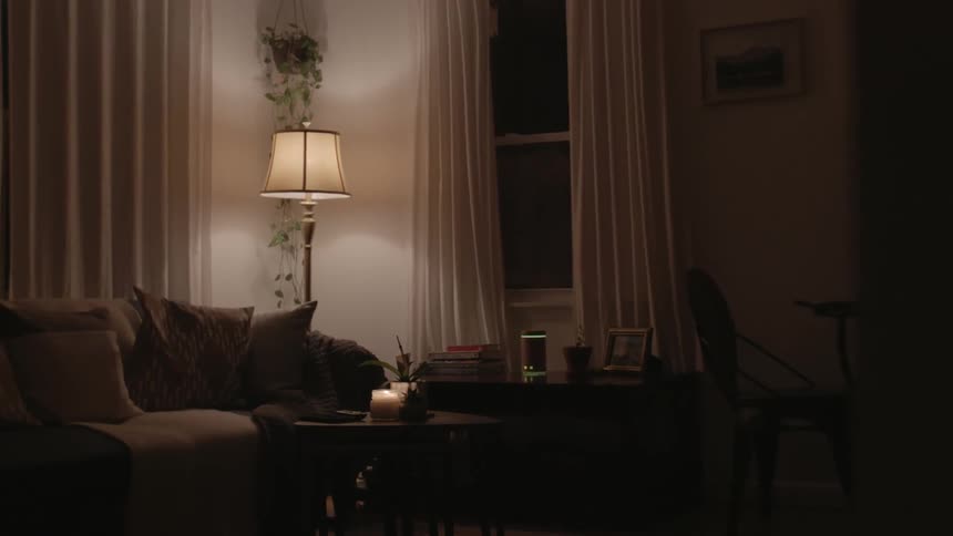 Woman walking into living room to sit down on couch and play with her smartphone