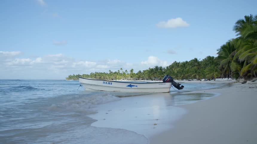 Small boat with a motor sits in the edge of the lake as waves roll in