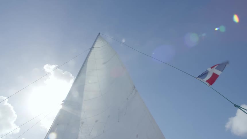 The sail of a sailboat jutting into the sky on a sunny day