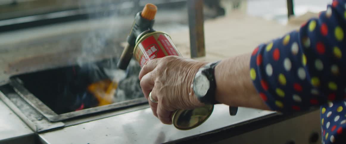 A man sprays fire into a metal bin of a cart
