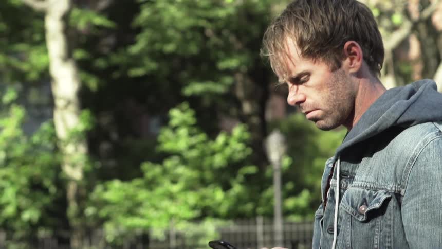 Man lifts cell phone to take photo in neighborhood