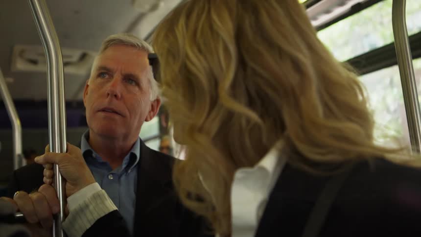 A man and woman standing and talking on a bus