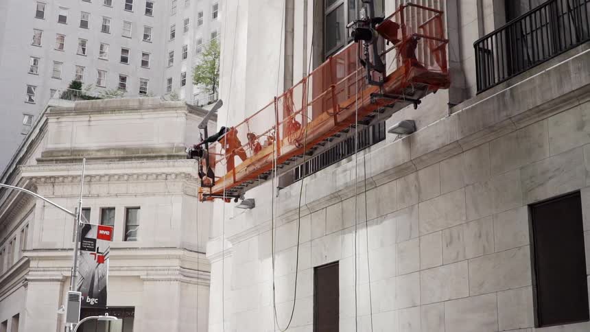 Two people on scaffolding next to a building