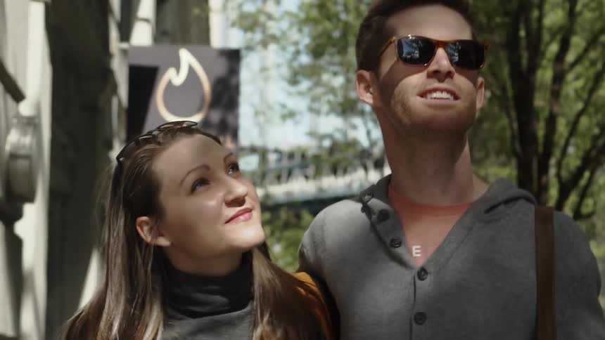 A man and woman walk down the street with their arms around one another
