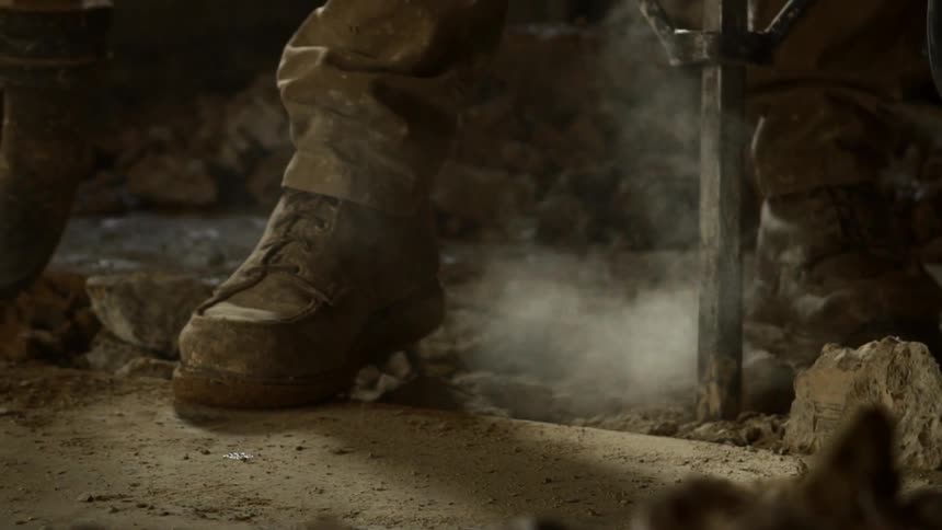 Person uses jackhammer to break up concrete sending dust into the air