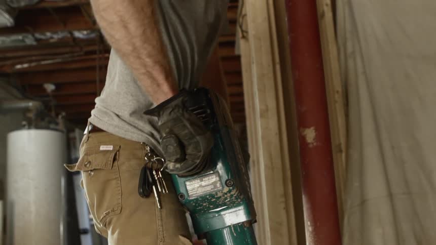 A man uses a jack hammer on a construction site