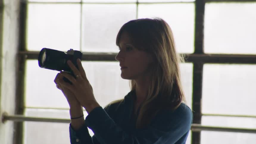 Woman with camera takes photos in industrial loft space