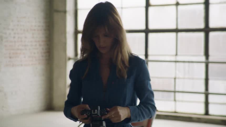 Woman walking across office holding camera looking at photos