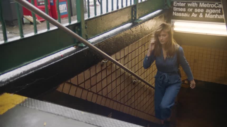 A woman walks up the steps from the subway and into a city neighborhood