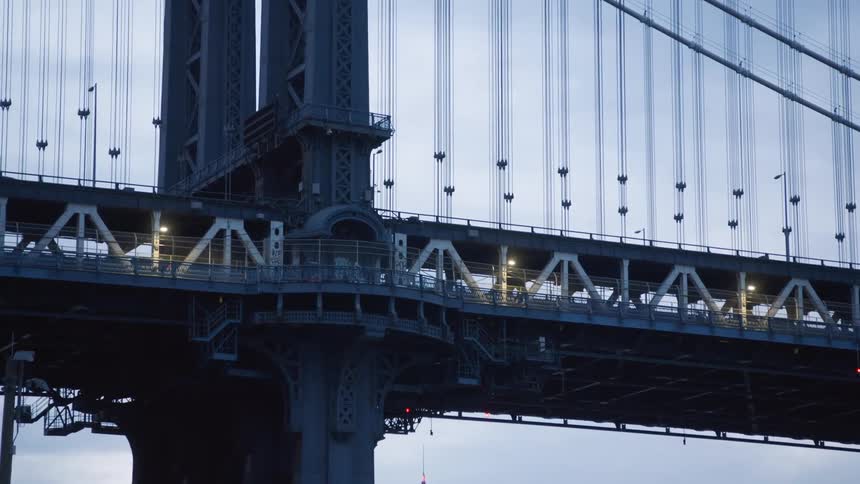 Cyclists riding their bicycles across the lower level of a bridge as traffic passes on the higher level