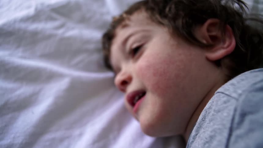 A little boy lying down talks