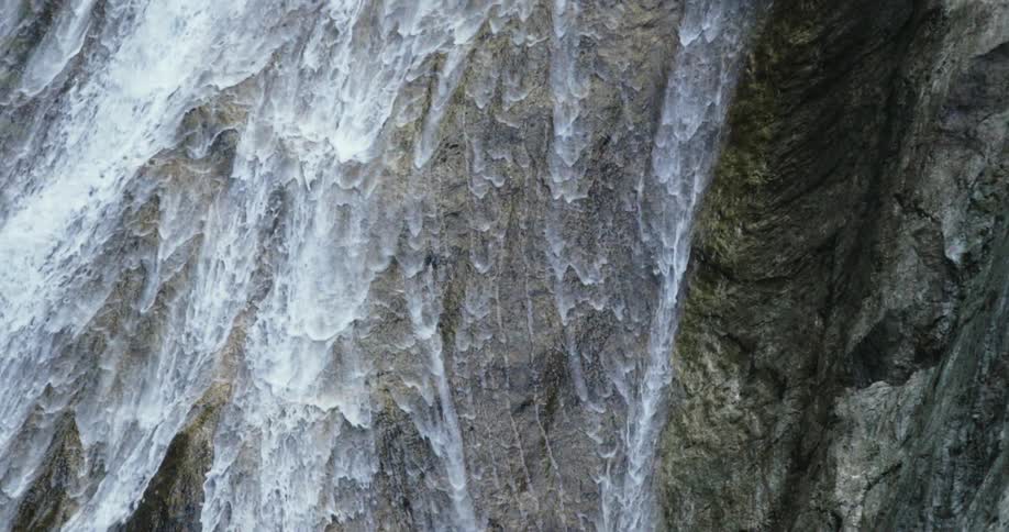 Water flows and rushes down the face of a rocky cliff