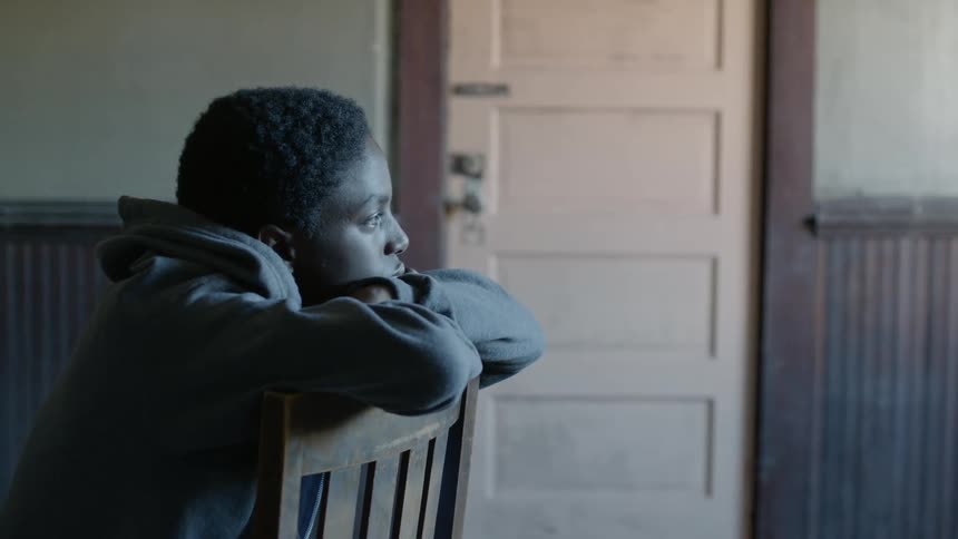 A young man sits backward in a wooden chair