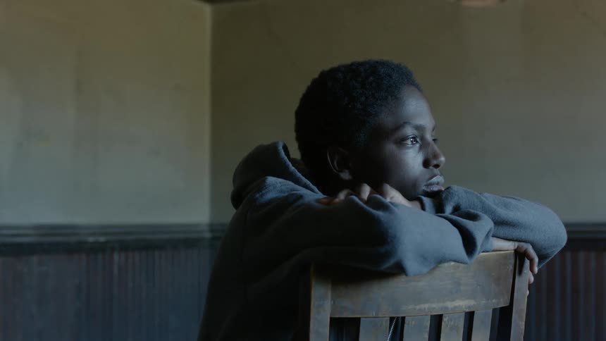 A man sits backward in a chair with his face rested on his arms