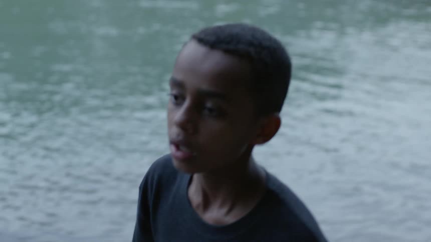 A boy and a girl walking by a lake