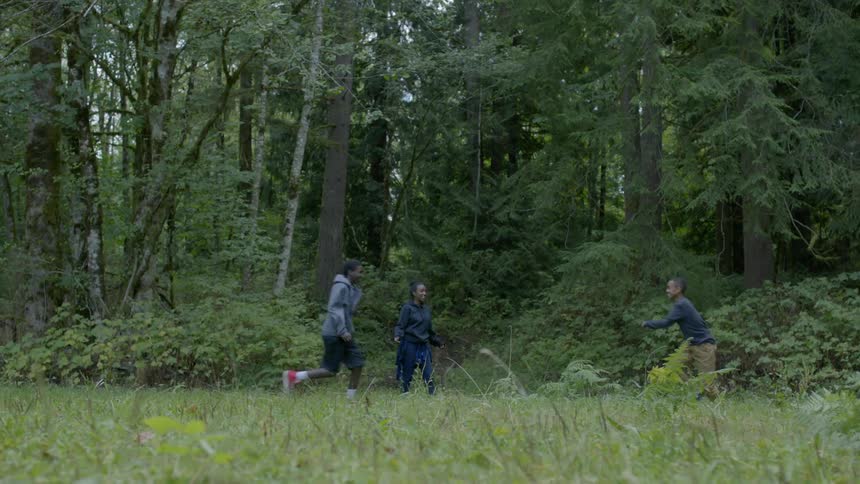Two boys play fight as another referees in a forests