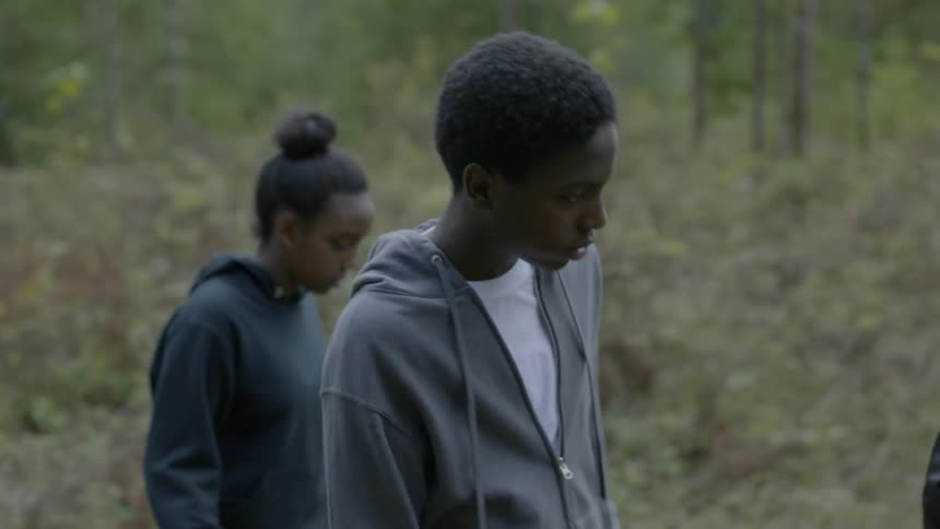 Three black teens walk through a forested area