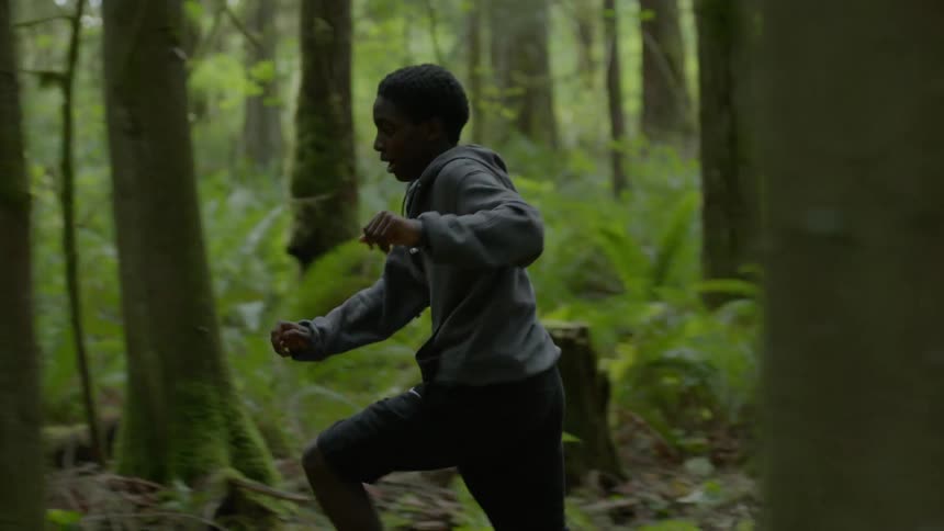 Two kids run through the forest