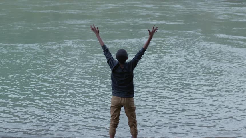 A boy throwing mud into a lake
