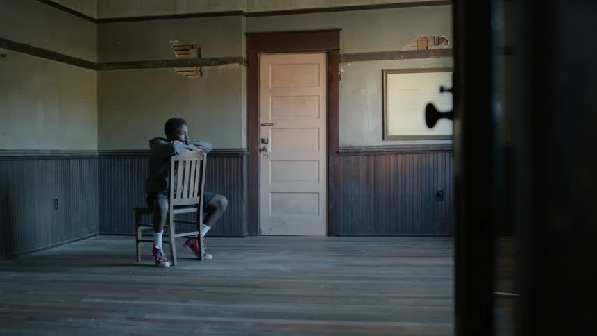 Man sits on chair in empty run down apartment room