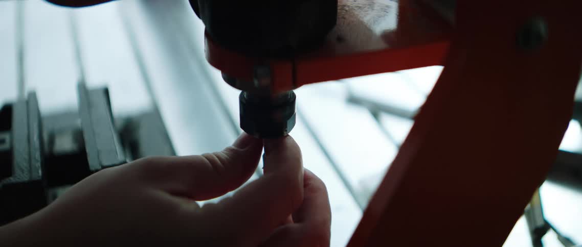 Hands insert a pin then tighten to secure a workbench for a power tool