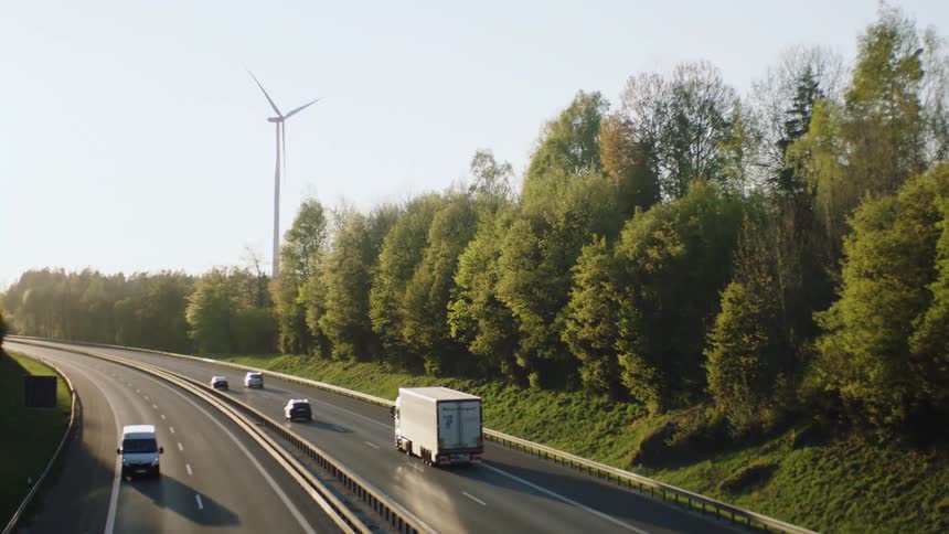 Traffic traveling along a freeway flanked by trees during the day