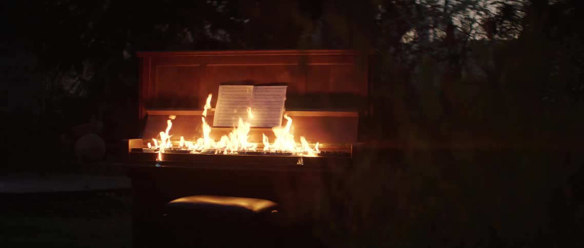 Upright piano keyboard with keyboard lighting on fire in forest at night