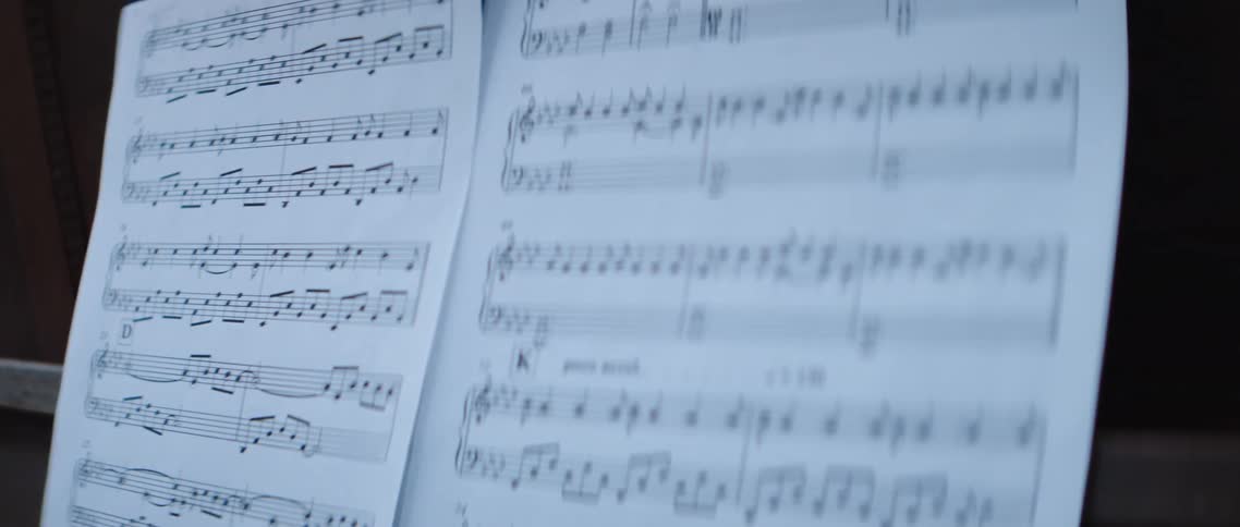 Music sheets over the keyboard of a piano sitting outdoors
