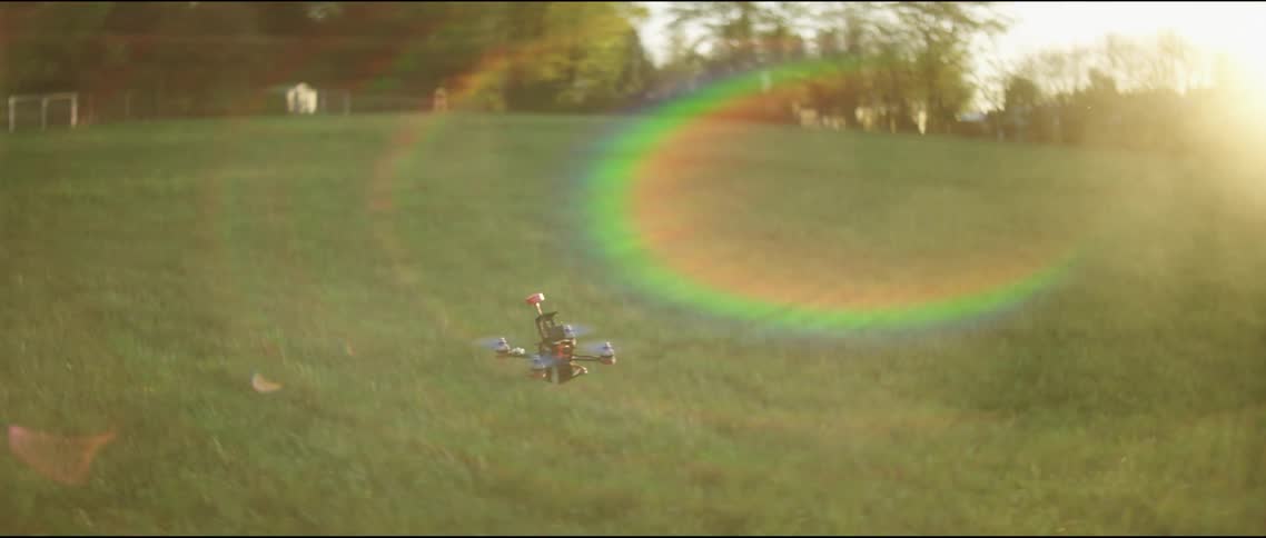 Small drone flying over lawn at sunrise