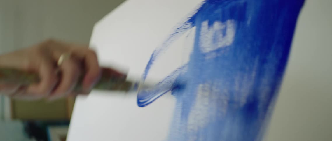 Painter uses a brush to paint a canvas in a studio