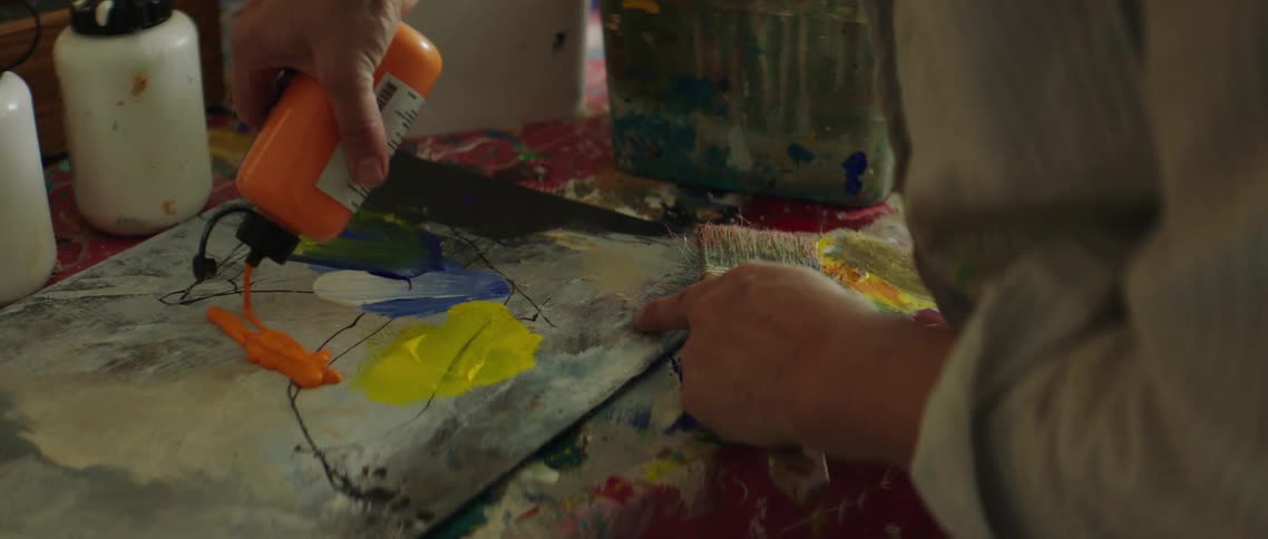 A man puts orange paint on a board