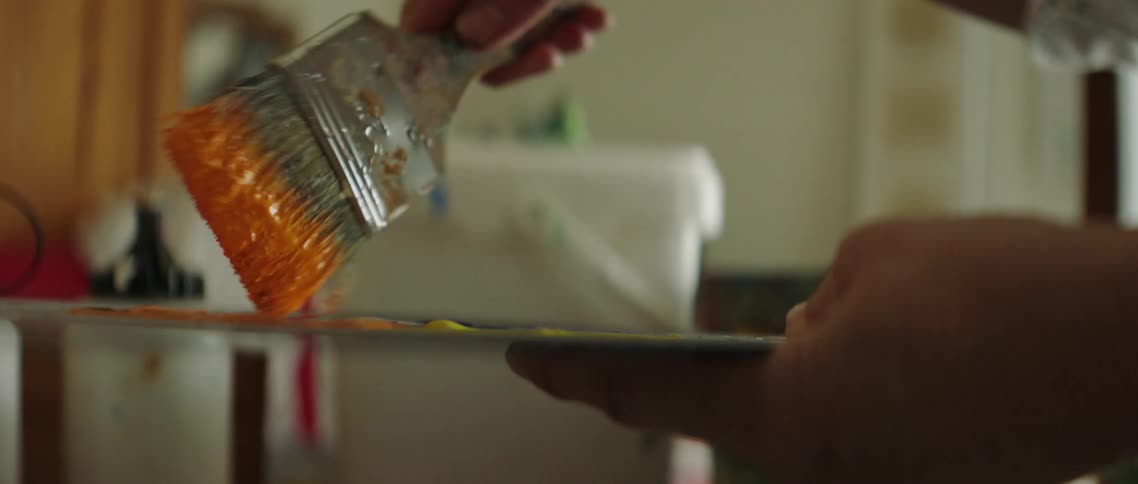 A painter mixes paint colors on a palette