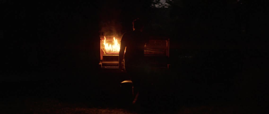 A young man lights a piano on fire