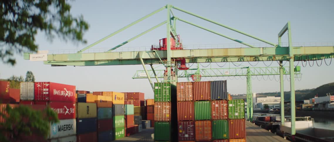 A crane is moving above shipping containers