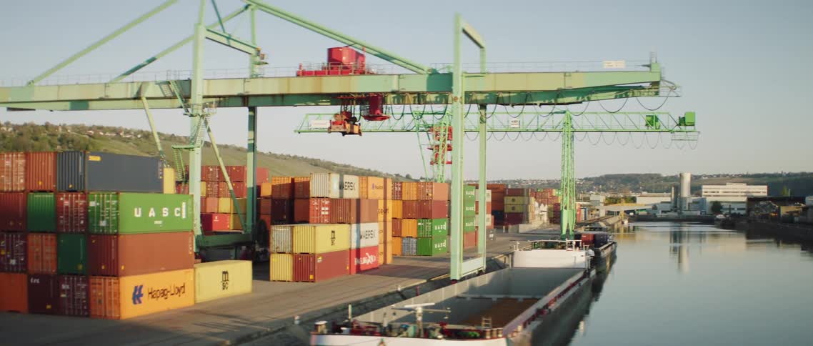 A barge sits by a shipping crane in a port