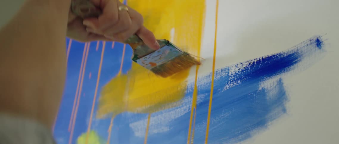 Artist brushing canvas with wide brush