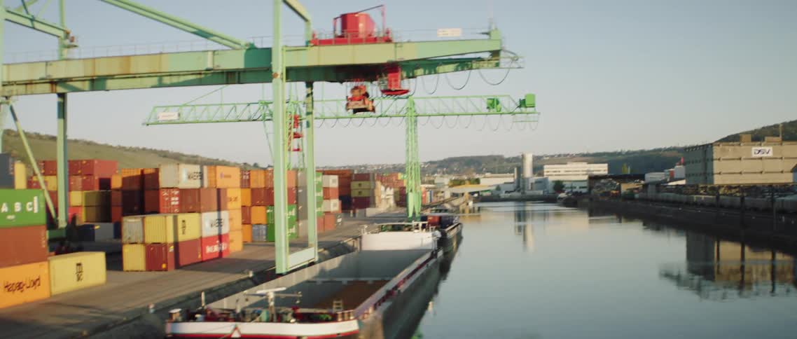 A crane runs above shipping containers in a shipyard