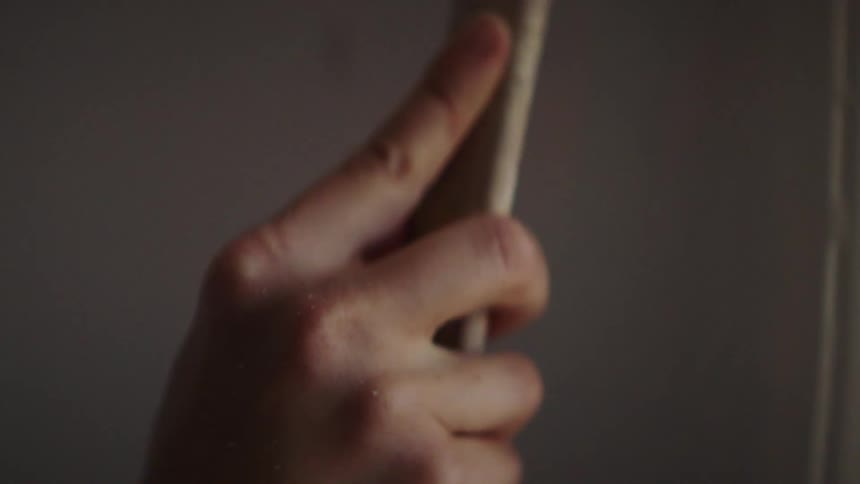 A white male uses a long paint brush to paint a door frame indoors