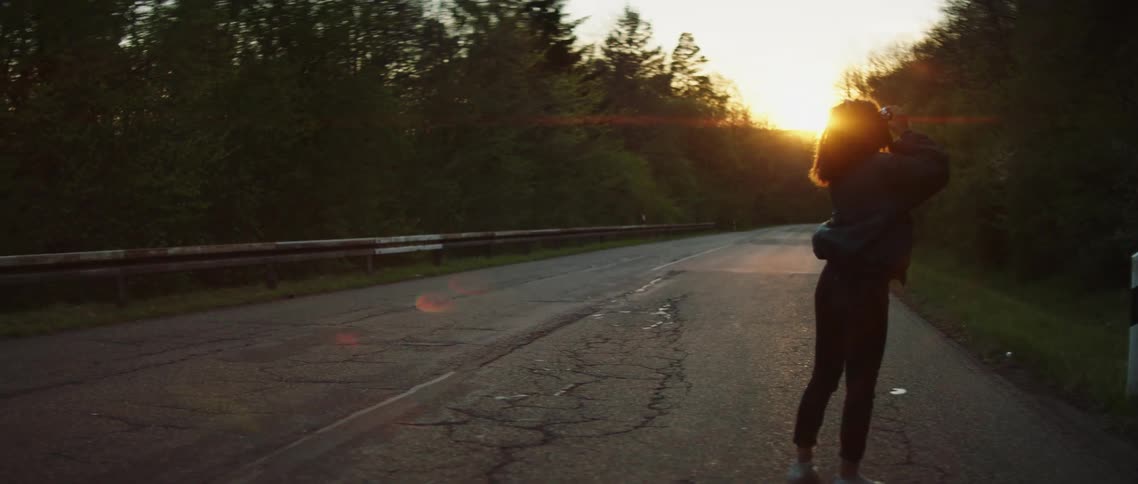 Photographer takes pictures of pine tree forest standing on a country road at sunset