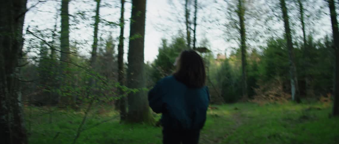 A hispanic woman walks in the woods and stops to take a picture with a camera