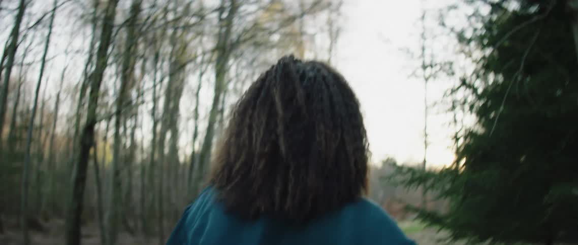 Woman walking on path through forest