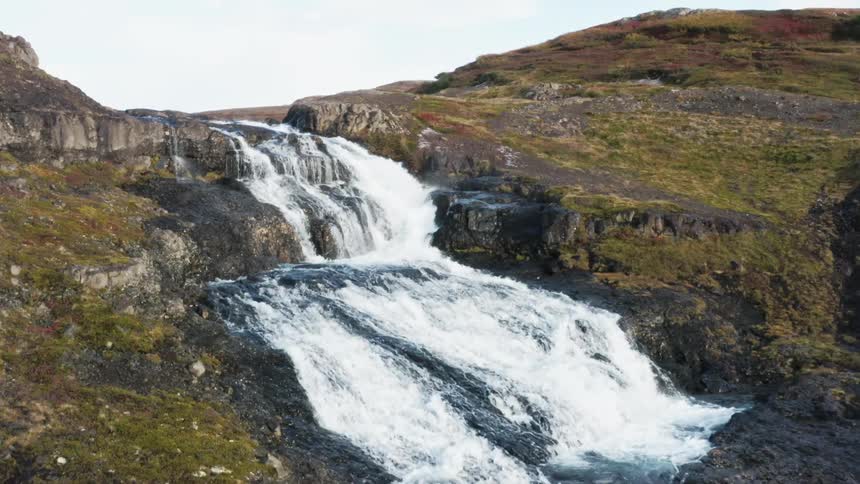 A canyon waterfall has multiple levels feeding into a river