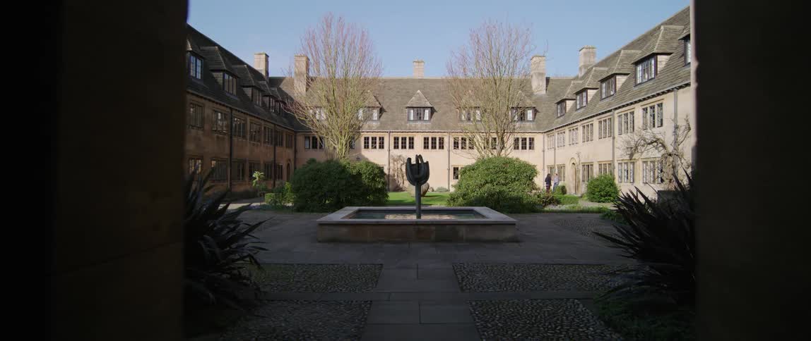 A fountain lies in the courtyard area surrounded on three sides by a building