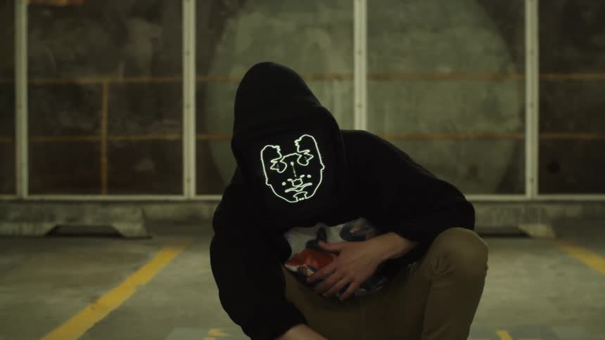 Person wearing animated digital face mask rapping in parking garage