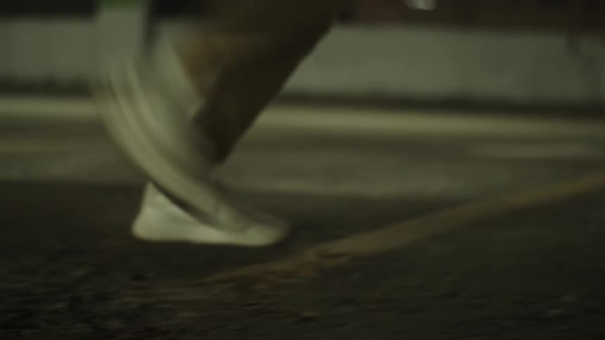Person sidestepping across pavement at night
